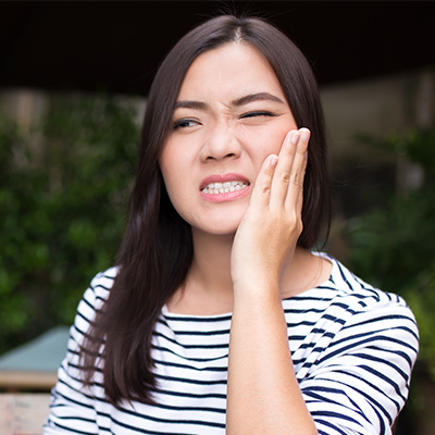 Woman grimacing and holding cheek